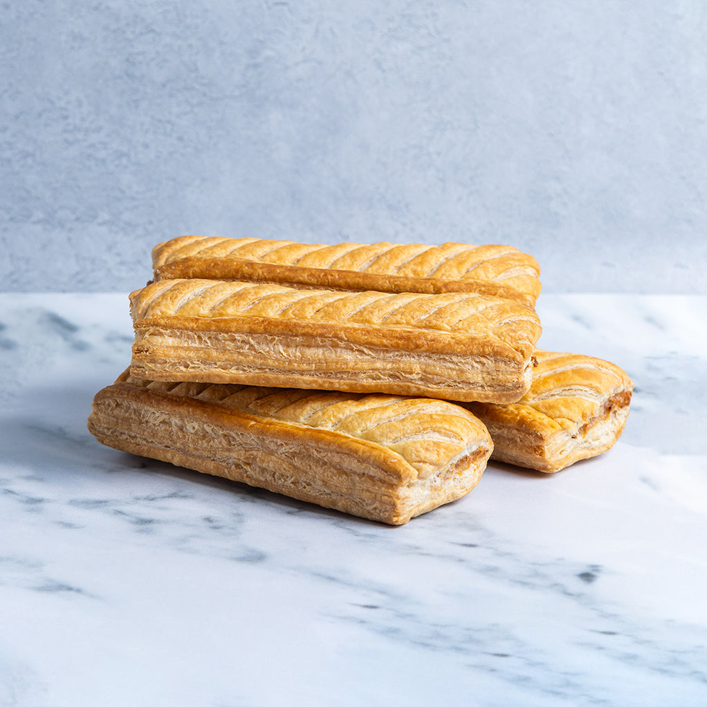 Stack of 4 sausage rolls on a marble surface 