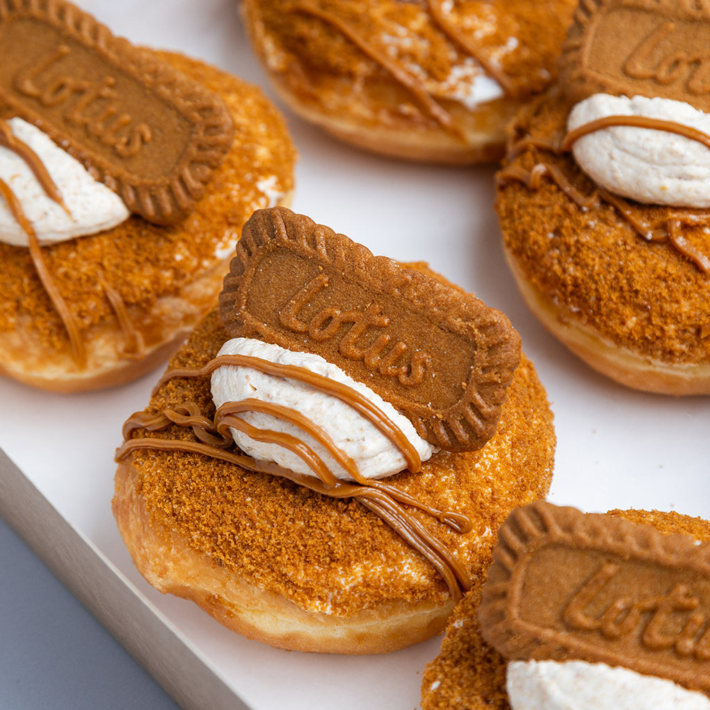 Donuts with Lotus cookie pieces and cream on a white surface