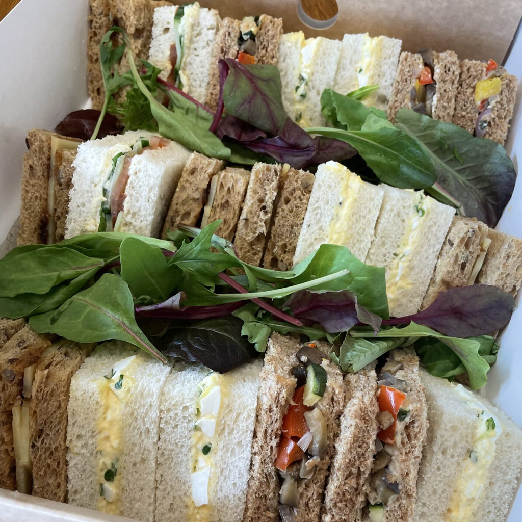 Assorted finger sandwiches with greens in a box