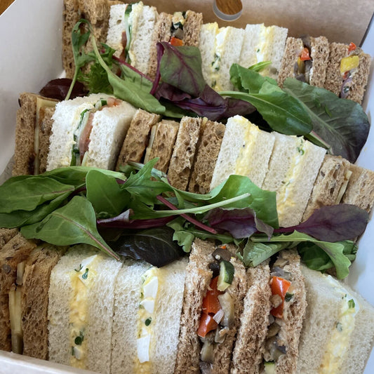 Assorted finger sandwiches with greens in a box