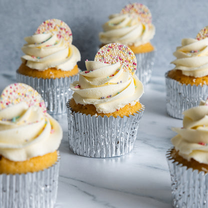 Cupcakes with white frosting and sprinkles on a marble surface