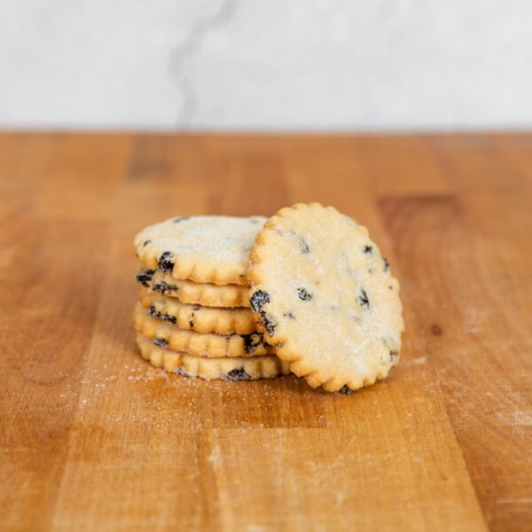 A stack of spicy fruited shortbread sugared round biscuits on a wodden table top