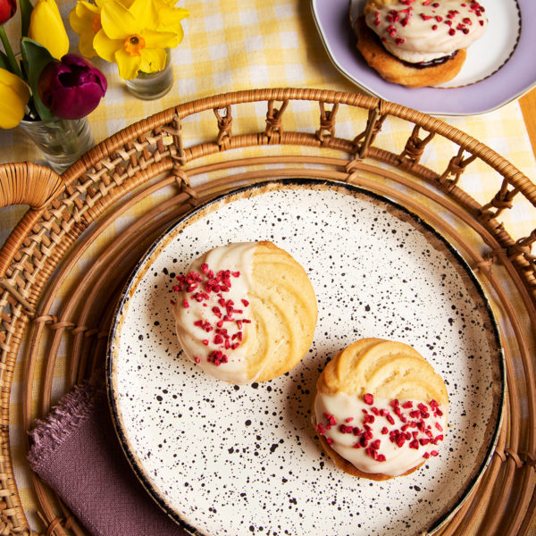 two white chocolate & raspberry viennese biscuits shot from above to showcase the freeze dried raspberries and white chocolate.