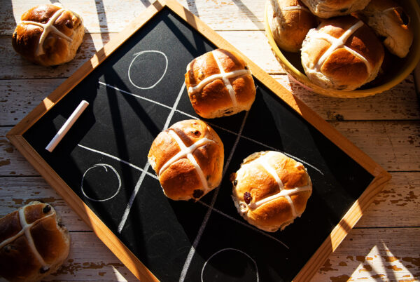 Three hot cross buns on a blackboard, representing crosses in a game of naughts and crosses