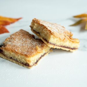 Bramble Bakewell Slice with layers of buttery pastry, tangy blackberry jam, and soft almond sponge topped with white icing.